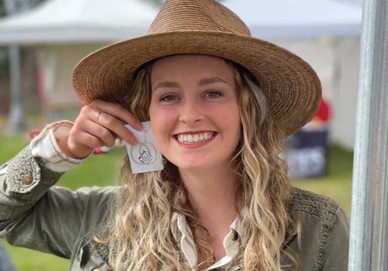 Woman with hat holding up earings