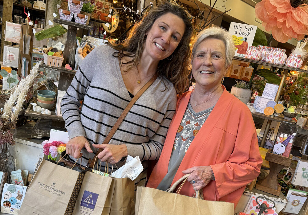 two women in a store with shopping bags